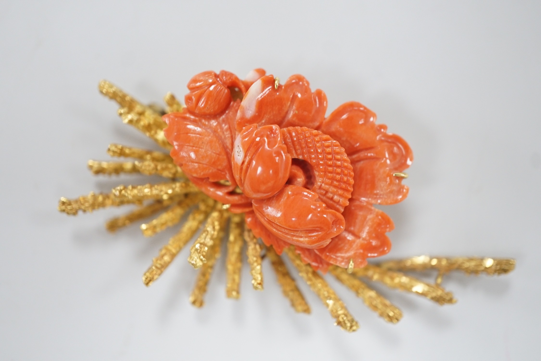 A 1970's? textured 14k yellow metal and carved coral mounted floral spray brooch, 62mm, gross weight 17.1 grams.
